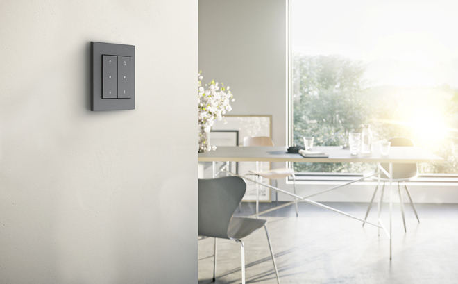 Gira System 3000 Jalousie- und Schaltuhr Display in Anthrazit mit E2-Rahmen für den flachen Einbau, an der Wand eines hellen Essbereichs